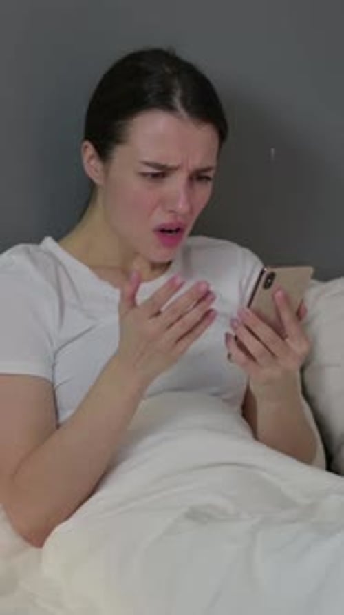 Failure, Young Woman Reacting to Loss on Smartphone in Bed , Vertical Video