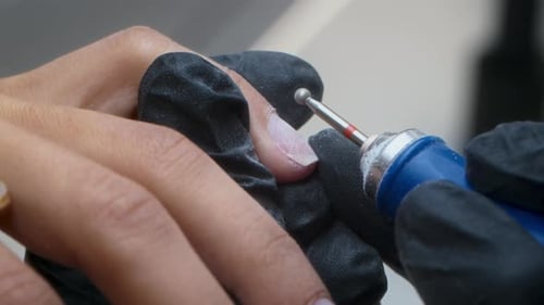 Cosmetic Manicurist Shapes Fingernail with Electric File