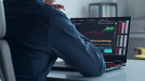 Cryptocurrency Trader at His Workplace in Front of a Computer Laptop Monitor with Stock Profit Chart