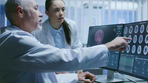 Doctors analyzing brain scans on computer screens