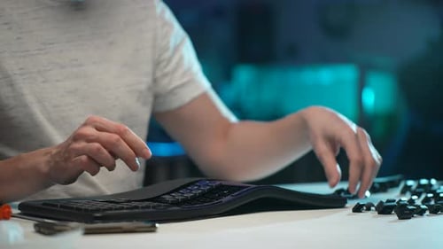 Plan rapproché recadré d'un homme méconnaissable assemblant un clavier démonté après l'avoir nettoyé