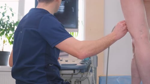 Un médico masculino realiza una ecografía de las venas varicosas en las piernas de un paciente