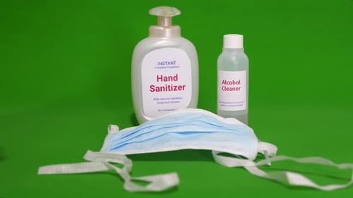 Mask and alcohol liquid sanitizer picked up by hand of woman using for protection by Coronavirus inf