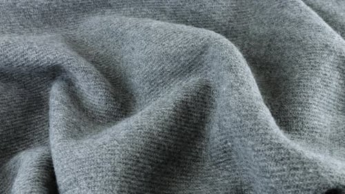 Top view of the soft folds of textured gray wool fabric rotated on the display case.