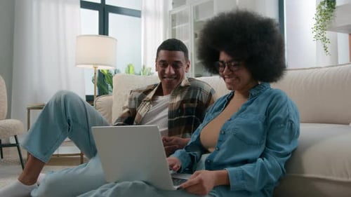 Smiling Couple Relaxing Together with Laptop Indoors