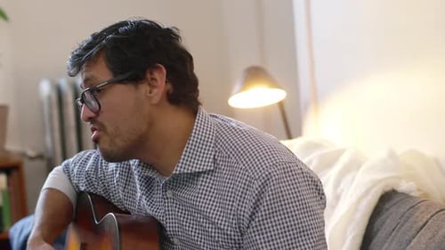 Man playing guitar inside a bright home