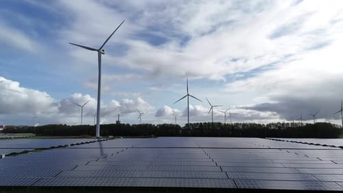 Solar panel park near city Delfzijl in the Netherlands with wind turbines