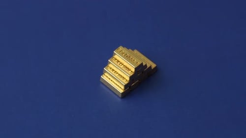 Shiny Gold Bars Stacked Pyramid on Blue Surface