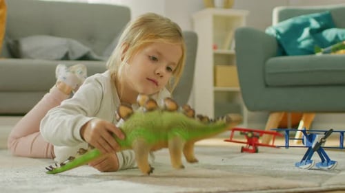Little Girl Plays with Dinosaur Toy on Floor
