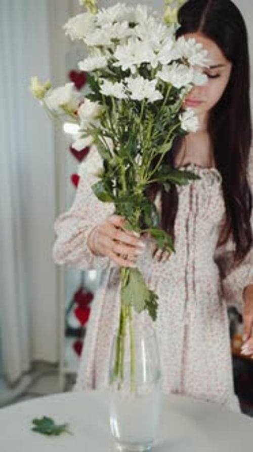 Young Woman Arranging White Flowers in Vase