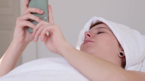 Woman Relaxing, Using Phone in White Spa Setting
