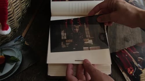 Las manos insertan una foto navideña impresa en un álbum de fotos familiar