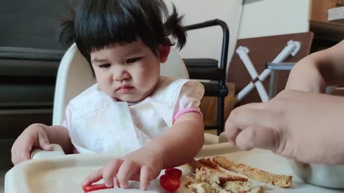 Sweet Infant Eating Toast Sticks in High Chair