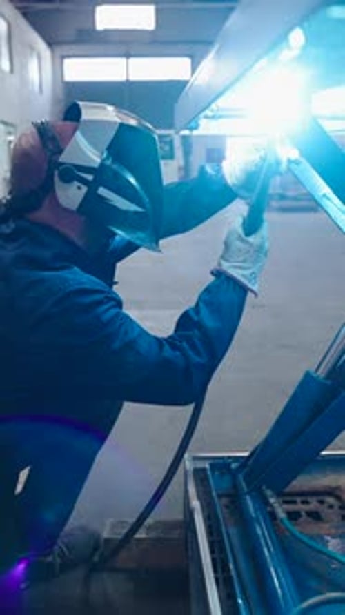 Man Welding Metal in a Workshop with Gear