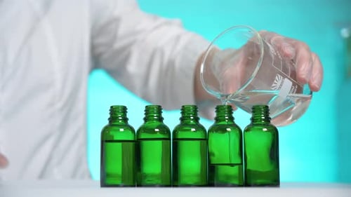 Liquid Being Poured into Green Glass Bottles