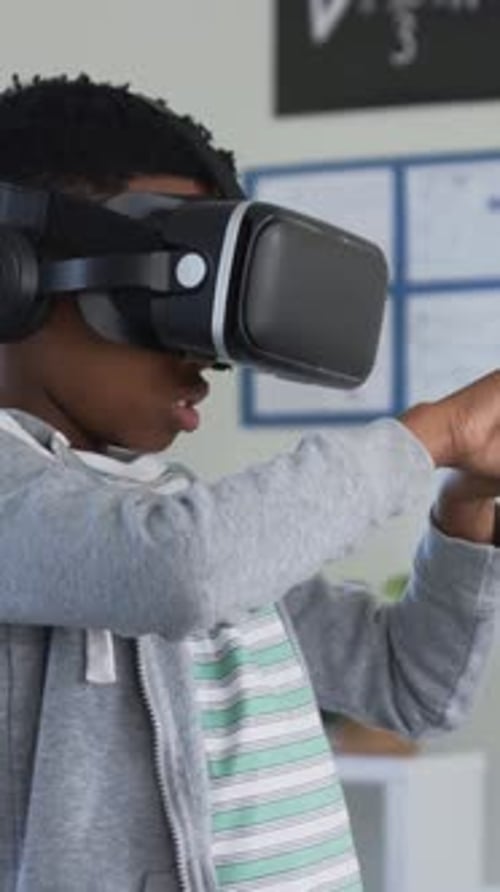 Interacting student in striped tee, gray hoodie using VR headset-headphones in classroom math board