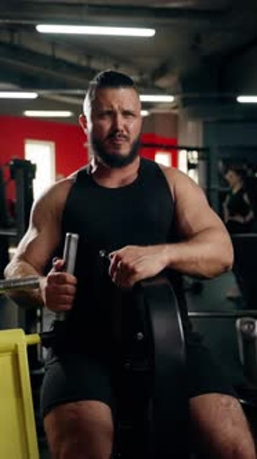 Strong Man Gripping Rowing Machine Handle with a Determined Look in a Modern Gym