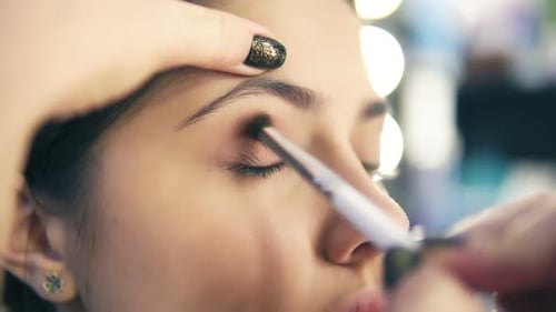 Closeup view of professional makeup artist hands using makeup brush to apply eye shadows