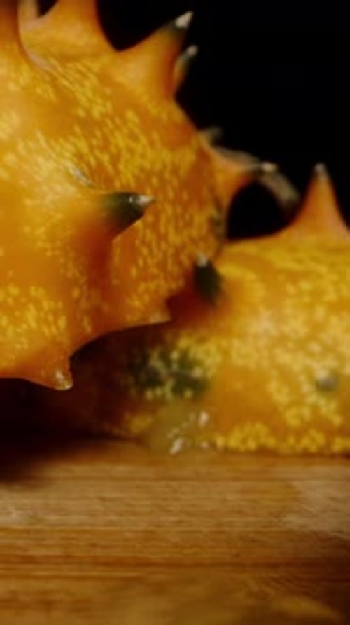 Vertical video. Sliced Kiwano cucumbers on the table, sharp pieces on a black background. Dolly