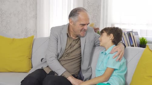 Grandfather and Grandson Talk and Hug on Couch