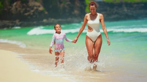 A Mother and Small Daughter Enjoying on Exotic Island Playfully Splashing Running and Spinning on