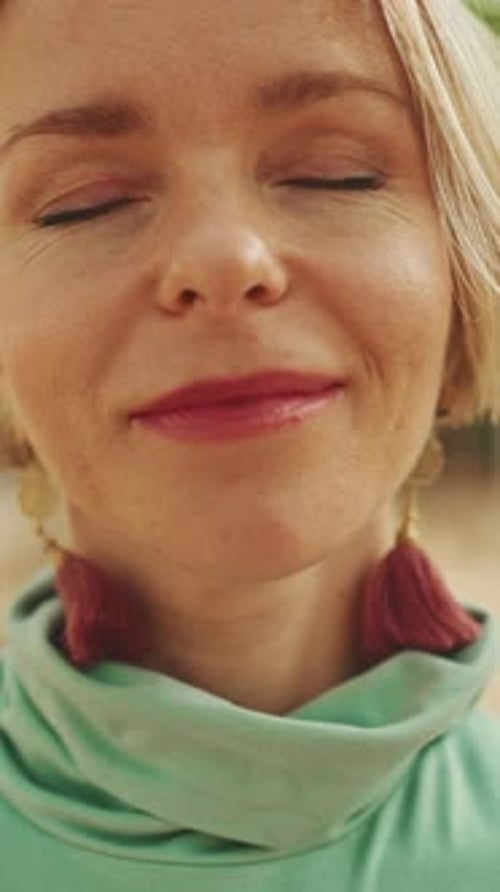 Close-up of an attractive happy woman opens her eyes, smiles looking at the camera