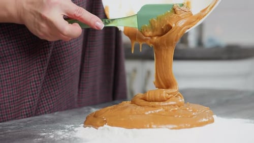 CloseUp of Woman Pouring Creamy Batter Into Flour with Green Spatula in Kitchen