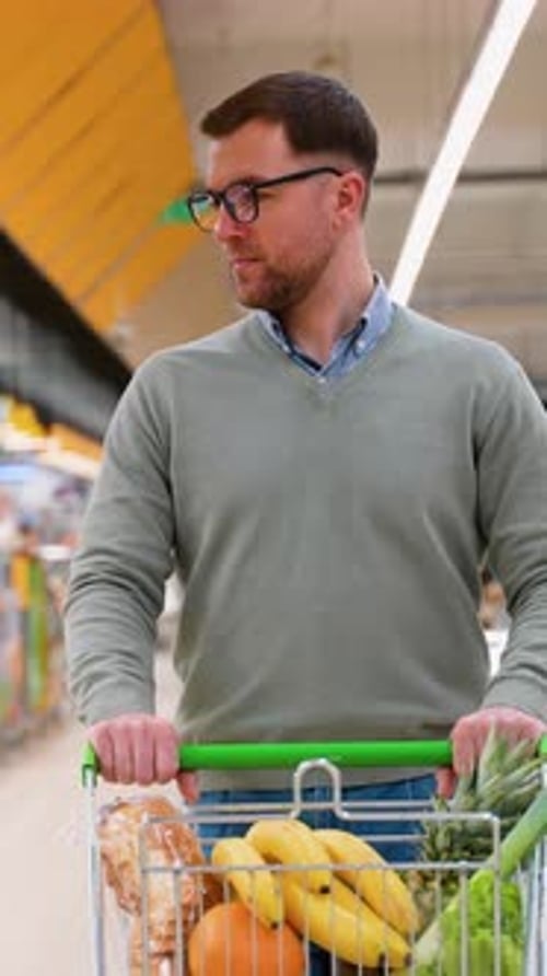 Man Pushing Shopping Cart in Grocery Store Aisle