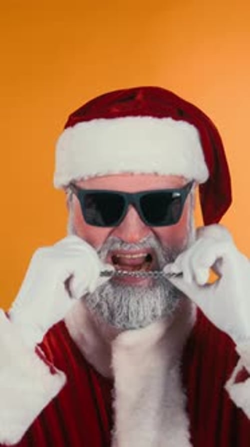 Vertical of Santa Biting Chain and Rocking out to Upbeat Music in Studio