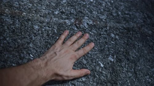 A Man 's Hand is Reaching Out Towards a Pile of Rocks
