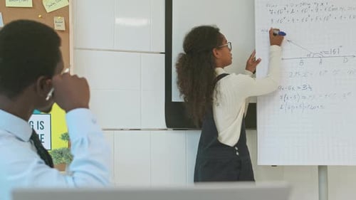 Girl Solving Math Problem with Teacher Assistance