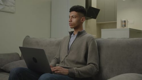 Young Adult Typing on Laptop Computer at Home