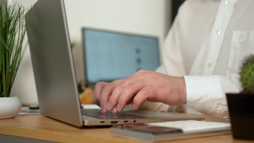 Mann, der im Büro arbeitet und auf einem Laptop tippt, wird auf den Schreibtisch gelegt und vom Notizbuch entfernt, Nahaufnahme