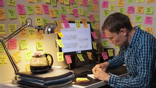 Busy Man Working at Desk With Computer and Notes