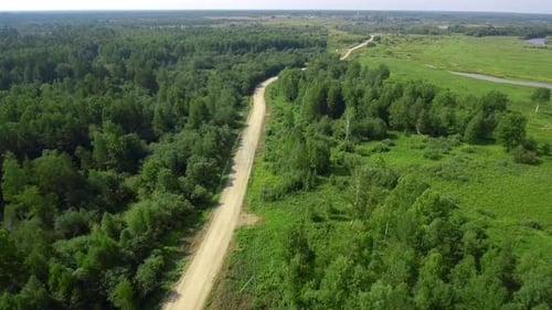 Panorama of road in forest area with green fields in summer