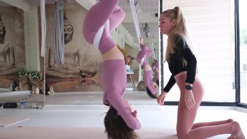 Woman Doing Aerial Yoga with an Instructor