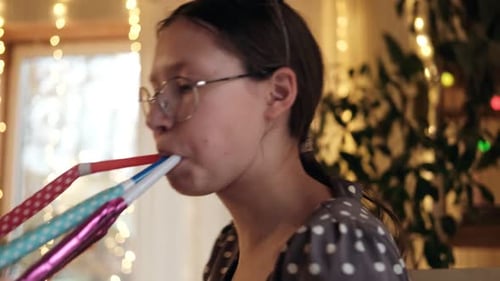 Teen Celebrates with Party Blowers Indoors