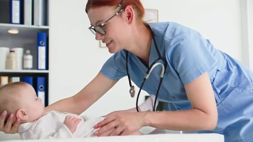 Doctor Examining Infant on Examination Table in Hospital