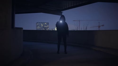 Mysterious Hooded Figure with Flashlight at Night