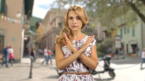 Portrait of a Serious Blond Woman Standing Outdoors Cross Her Arms As a Sign of Prohibition