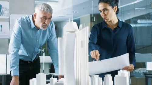 In the Architectural Bureau Two Professional Engineers Work on a Model of a City District. Urban Pl