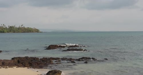 Felsige Strandszene, natürliches Reiseziel im Osten Thailands, mit schwarzen, klaren Vulkansteinen