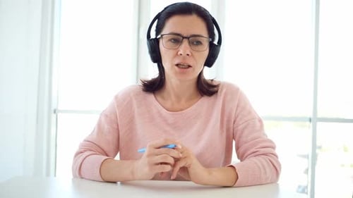 Woman Talks During Online Meeting Wearing Headphones
