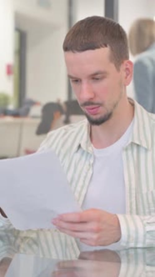 Enthusiastic Man Reading a Document in Office Setting