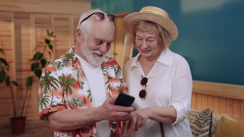 Senior Couple Looking at Smartphone Together Indoors