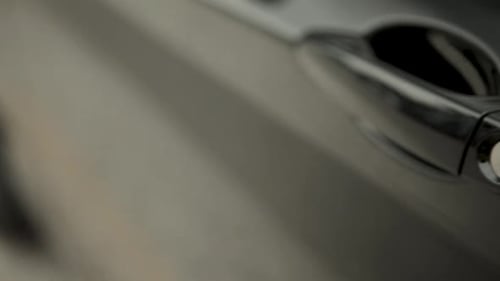 Close-up shot of a car's door handle in motion, showcasing a sleek