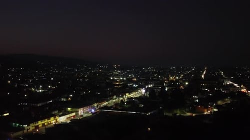 Aerial night scenic view of cityscape. Illuminated streets and buildings. Night life in small town.