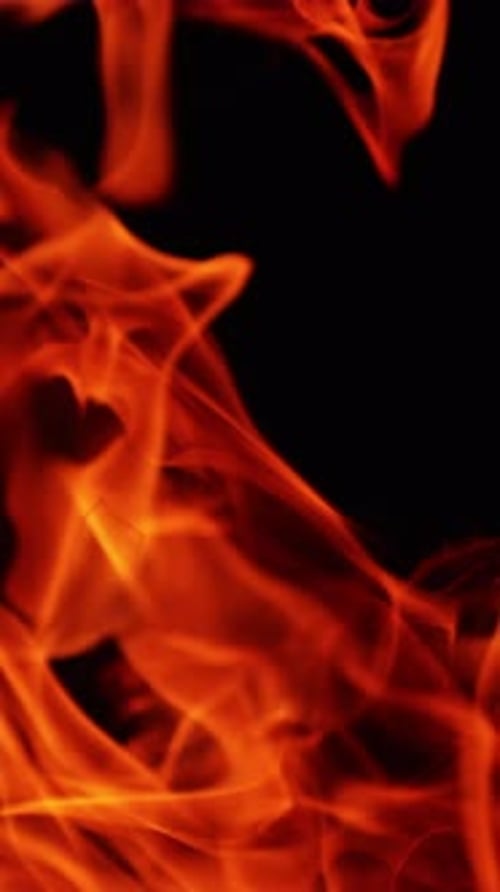 Quickly moving flames of bonfire in the wind outdoors. Fire burning at night. Close up.
