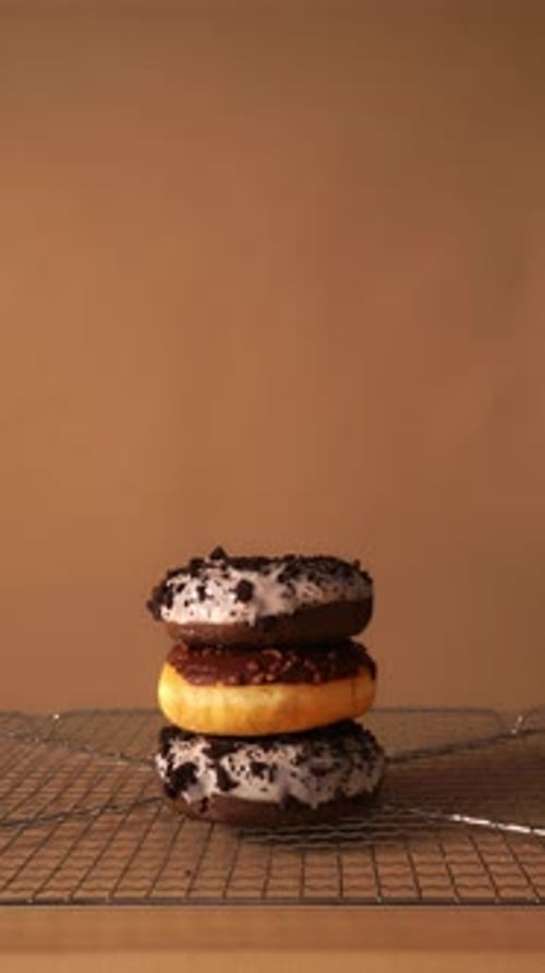 Hand Taking Donuts One by One from Stack on Cooling Rack Background