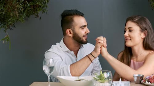 Affectionate couple holding hands over romantic restaurant meal